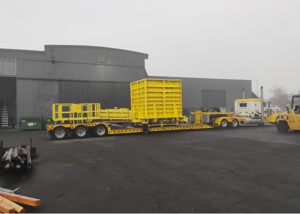 Oversized bright yellow steel form on lowboy trailer